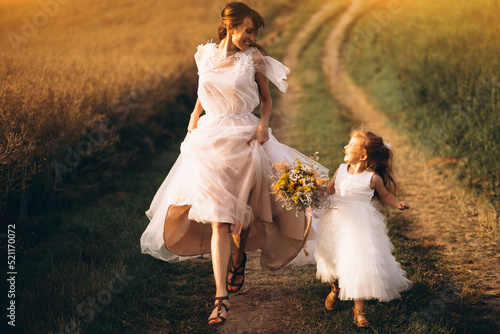 Mother with little daughter wearing beautiful dresses in the field