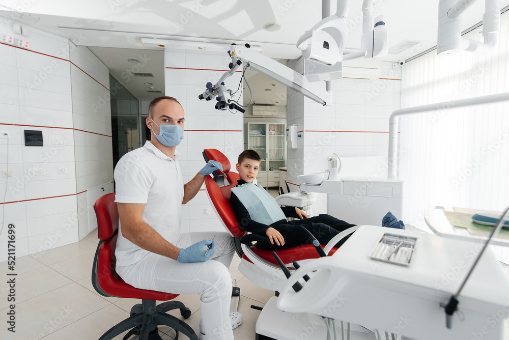 Fototapeta premium A young dentist examines and treats the teeth of an eight-year-old boy in modern white dentistry close-up. Dental prosthetics, treatment and teeth whitening. Modern dentistry. Prevention.