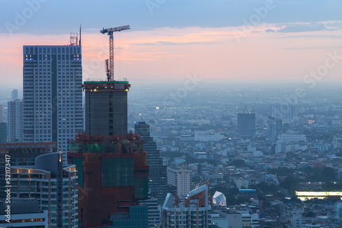 Construction site with cranes in the business district at dusk (Bangkok, Thailand)