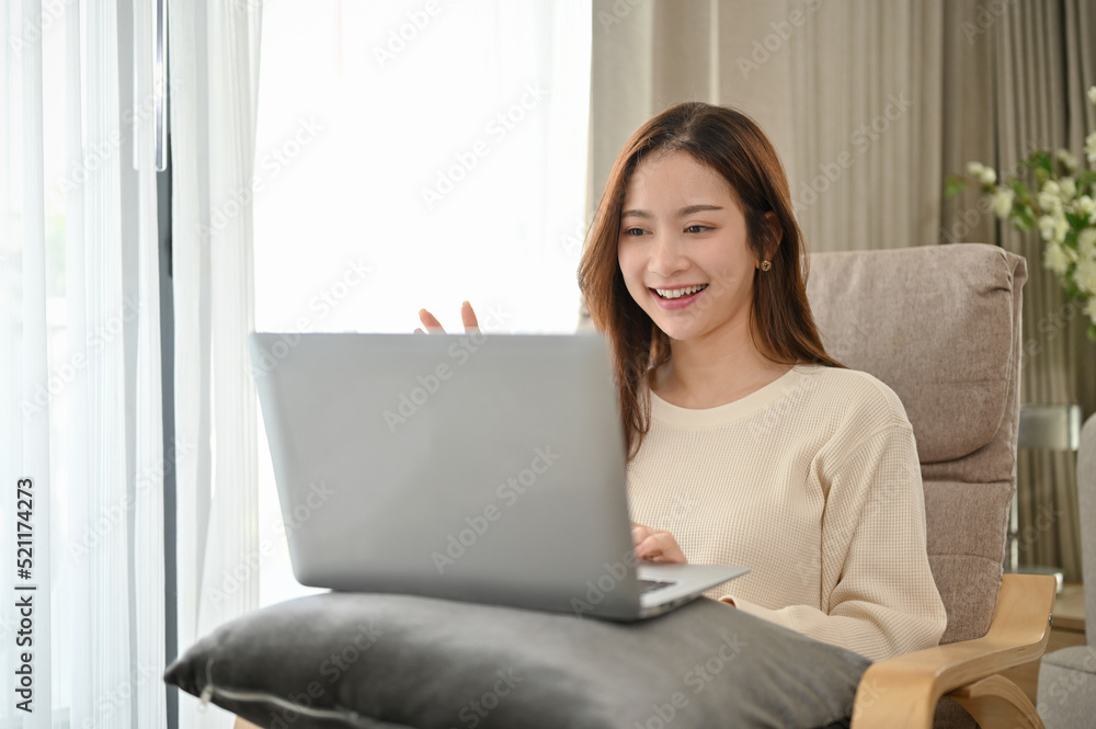Attractive young Asian female or college student in her living room while having a video call Attractive young Asian female or college student in her living room while having a video call