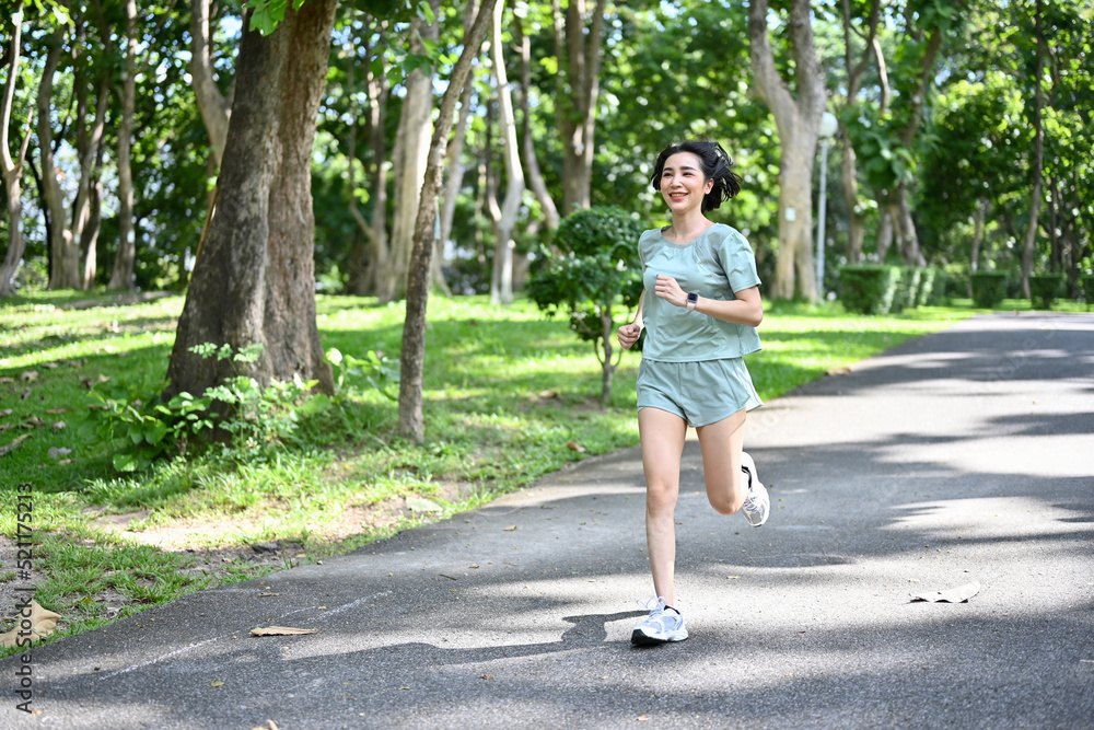 Healthy and fit Asian woman athlete running or jogging in the greenery park. Healthy and fit Asian woman athlete running or jogging in the greenery park.