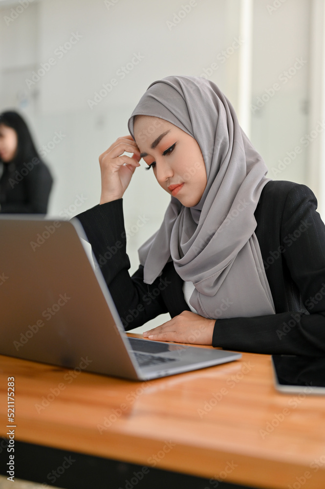 Stressed young Asian Muslim businesswoman working at her office desk. Stressed young Asian Muslim businesswoman working at her office desk.