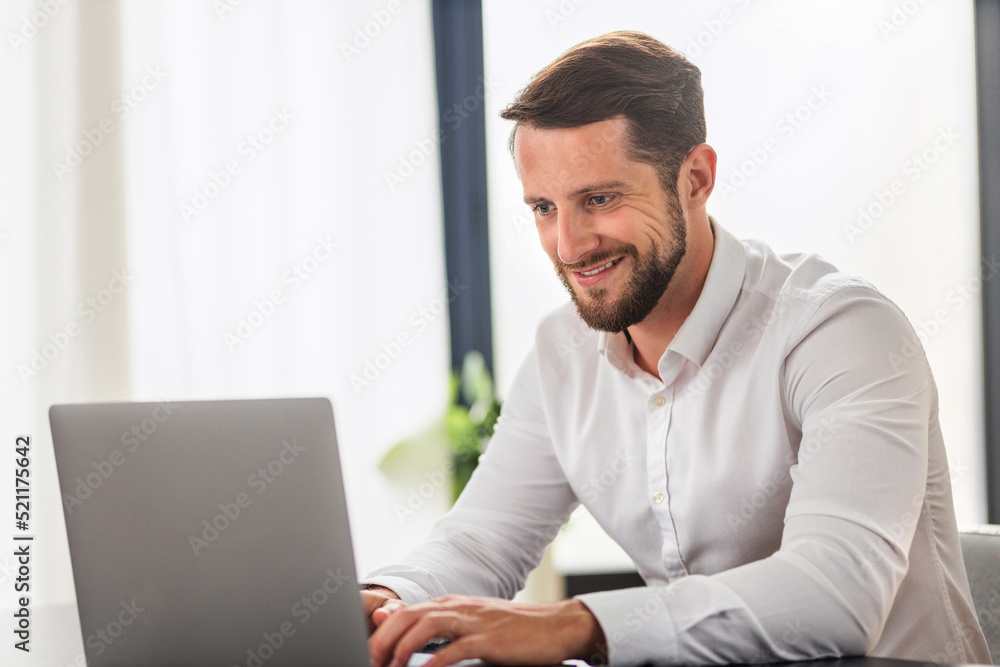 Successful businessman working using computer laptop sitting at the workplace in modern office. Bearded man entrepreneur in white shirt typing on keyboard, smiling Successful businessman working using computer laptop sitting at the workplace in modern office. Bearded man entrepreneur in white shirt typing on keyboard, smiling