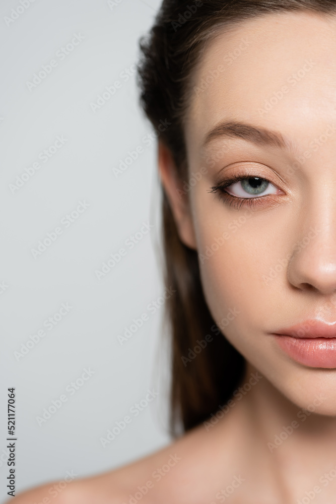 cropped view of young woman with blue eye and bare shoulder isolated on grey cropped view of young woman with blue eye and bare shoulder isolated on grey