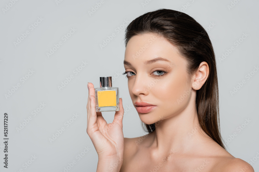 pretty young woman with bare shoulders holding bottle with perfume isolated on grey pretty young woman with bare shoulders holding bottle with perfume isolated on grey