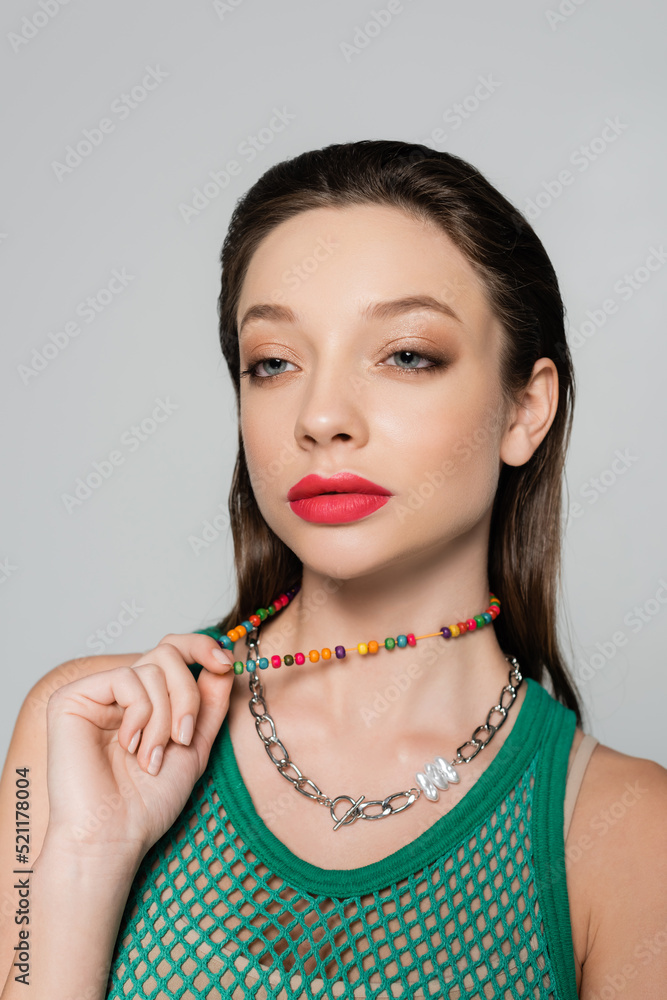 stylish model with red lips pulling beads necklace isolated on grey