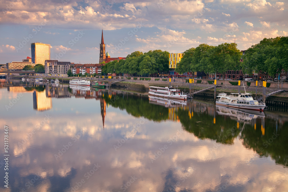 Bremen, Germany. Cityscape image of riverside Bremen, Germany with reflection of the St. Stephani Church in Weser River at summer sunrise.