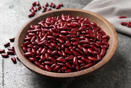 Raw red kidney beans in wooden bowl on grey table, closeup