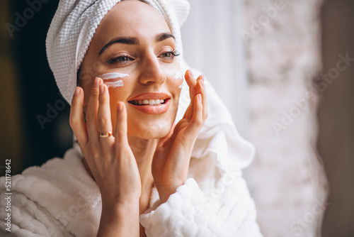 Woman applying moisturizing face cream photo