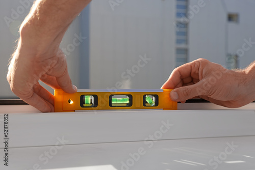 Fotografía Worker using bubble level after plastic window installation indoors, closeup