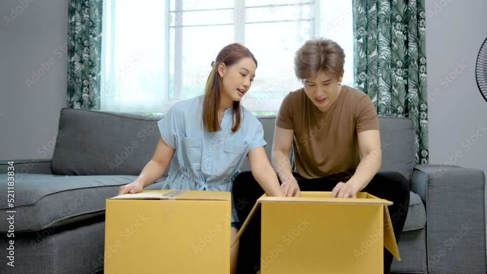 Asian young cute couple unpacking their stuff together in new house on moving day. Happy wife and husband open boxes parcels in own home after renovation. Relationship and relocation concept. Asian young cute couple unpacking their stuff together in new house on moving day. Happy wife and husband open boxes parcels in own home after renovation. Relationship and relocation concept.