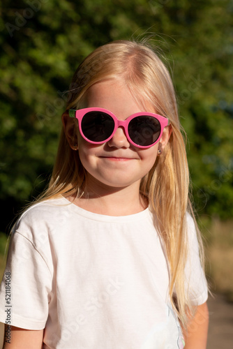 Cute little girl with blonde hair in pink sunglasses