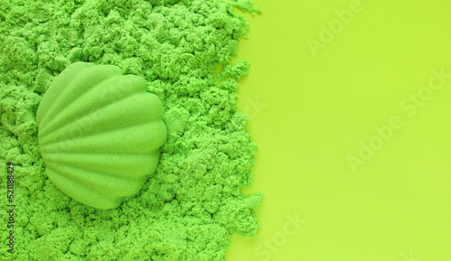 Obraz na płótnie Seashell sand figure made of green kinetic sand on light green paper background with place for text. Kids sensory game, development fine motor skills. Leisure and fun time on summer holidays concept. w salonie