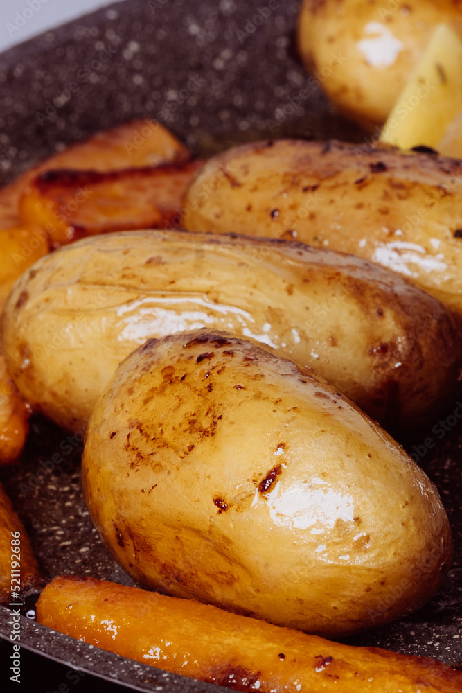 Close-up of appetizing oven baked
whole potatoes and carrots served on gray plate. Close-up of appetizing oven baked
whole potatoes and carrots served on gray plate.