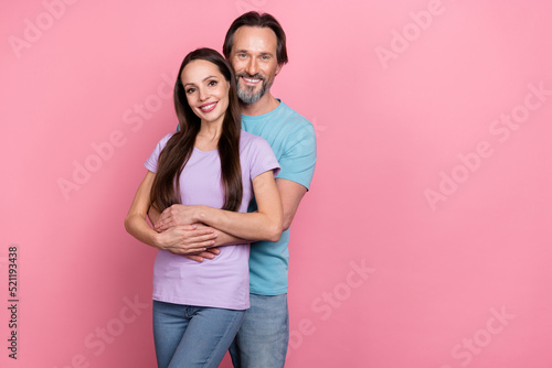 Photo of two lovely peaceful people hug have good mood look camera isolated on pink color background