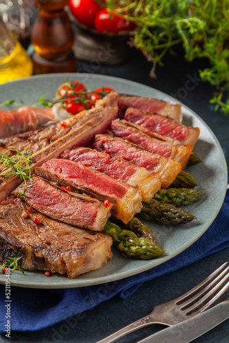 Grilled, medium-baked t-bone beef steak. Served with asparagus.