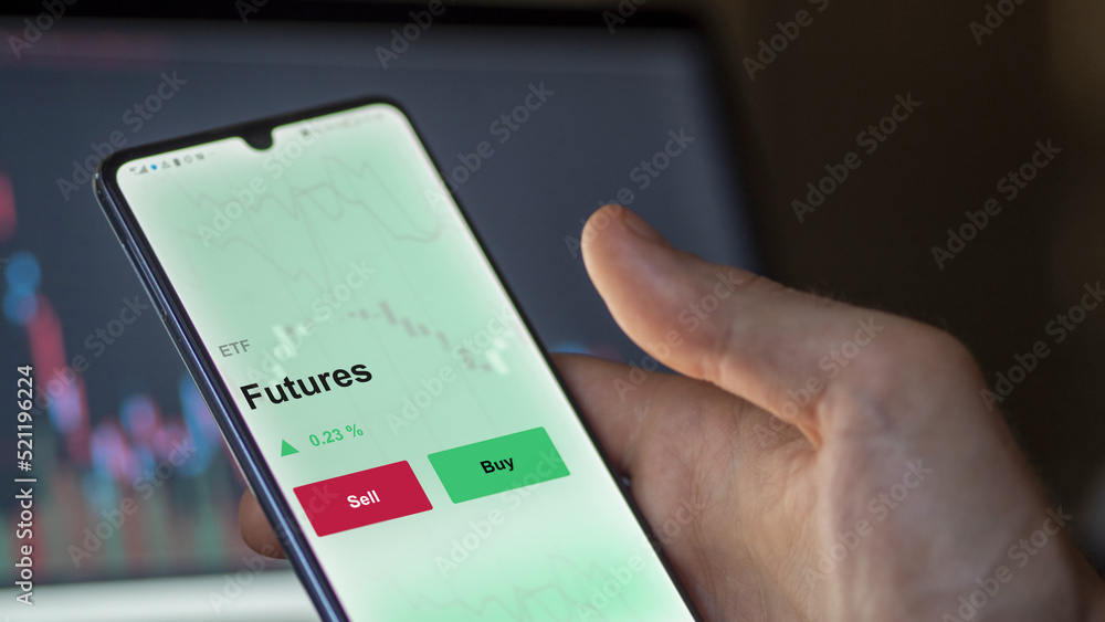 An investor's analyzing the futures etf fund on a screen. A phone shows the prices of an FUTURES ETF to invest in blue chips. An investor's analyzing the futures etf fund on a screen. A phone shows the prices of an FUTURES ETF to invest in blue chips.