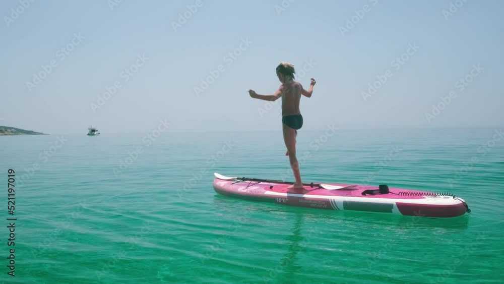 Kid balancing on one leg standing on paddle board. Kid balancing on one leg standing on paddle board.