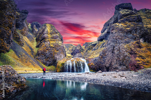 Amazing Icelandic Landscape. Photographer standing on canyon of river before majestic Stjornarfoss Waterfall.  Stjornarfoss waterfall  is one famous natural landmark and travel destination place. photo