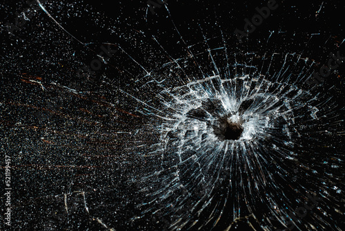 Bullet hole in a glass on the black background.closeup.