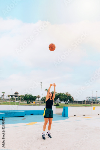 Athlete woman doing a basketball hoop shot on a street court. Lifestyle, sport and wellness