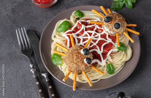 Cutlets look like a spiders with olives and straws, served with spaghetti pasta and tomato sauce. Halloween breakfast idea