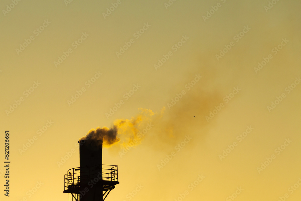 Fumaça saindo da chaminé da fábrica. Poluição do ar por fumaça saindo de uma chaminé de fábrica com o céu dourado do nascer do sol.