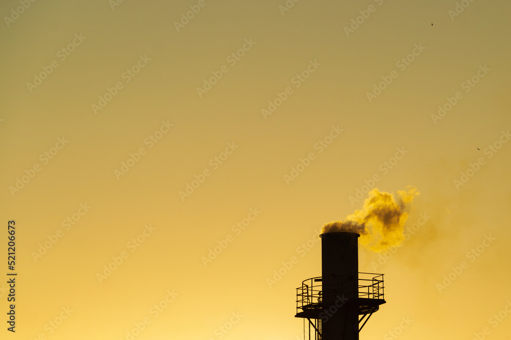 Fumaça saindo da chaminé da fábrica. Poluição do ar por fumaça saindo de uma chaminé de fábrica com o céu dourado do nascer do sol.