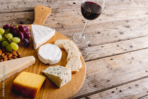 High angle view of various cheese with grapes and red wine on wooden table, copy space