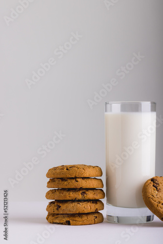 Milk in glass by stack of cookies against white background, copy space