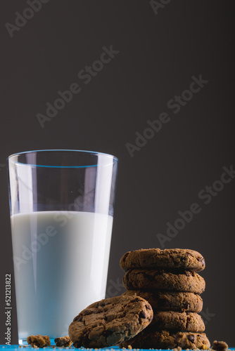Low angle view of milk glass by stacked cookies against gray background, copy space