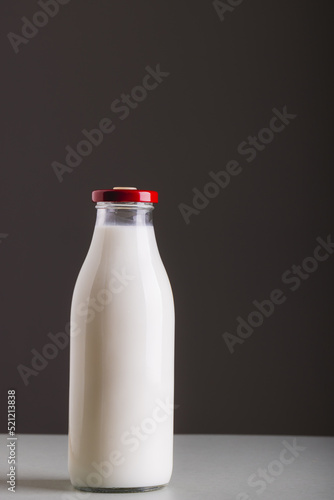 Milk in glass bottle on table against gray background with copy space