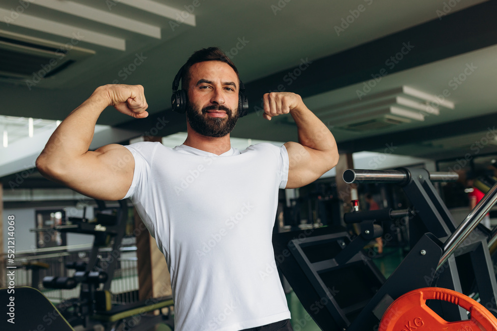 Athletic man in a white shirt shows off his muscles in the gym Athletic man in a white shirt shows off his muscles in the gym