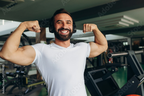 Athletic man in a white shirt shows off his muscles in the gym