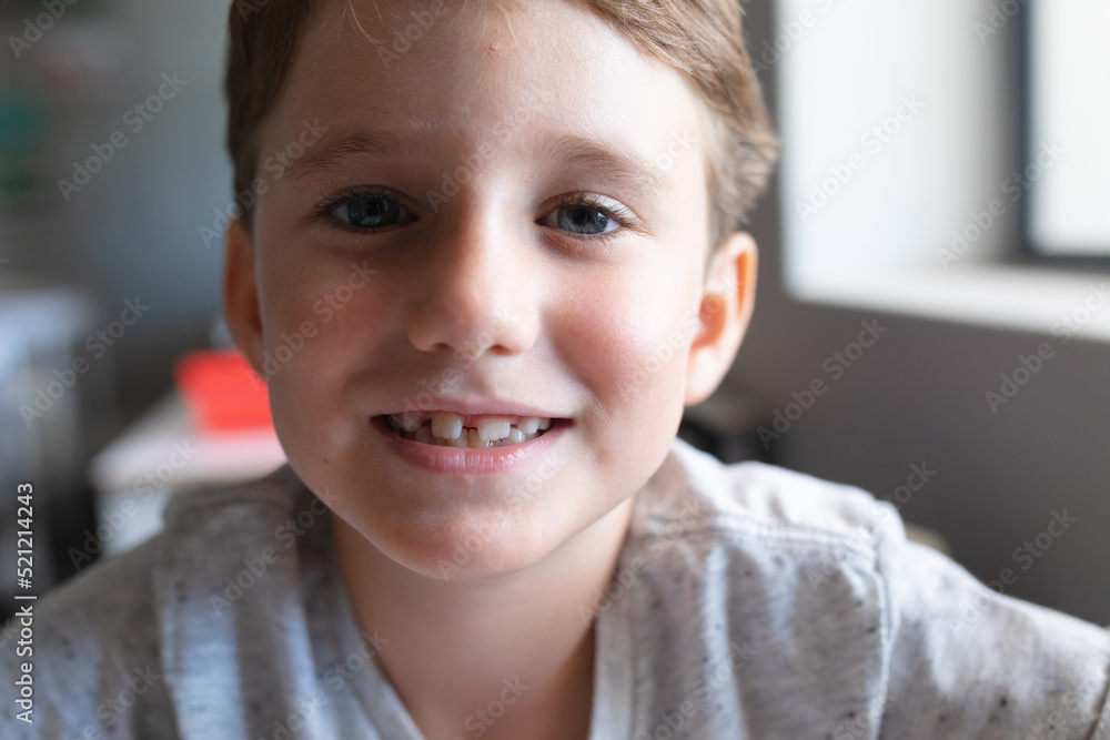 Close-up portrait of smiling elementary schoolboy sitting at desk in classroom Close-up portrait of smiling elementary schoolboy sitting at desk in classroom