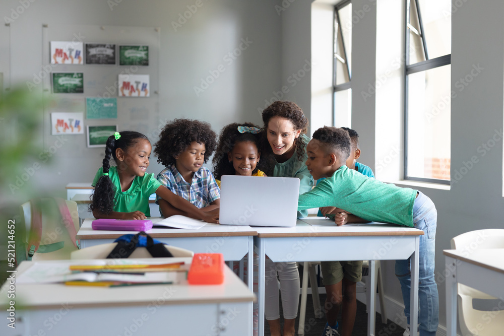 Caucasian young female teacher teaching laptop to african american elementary students Caucasian young female teacher teaching laptop to african american elementary students