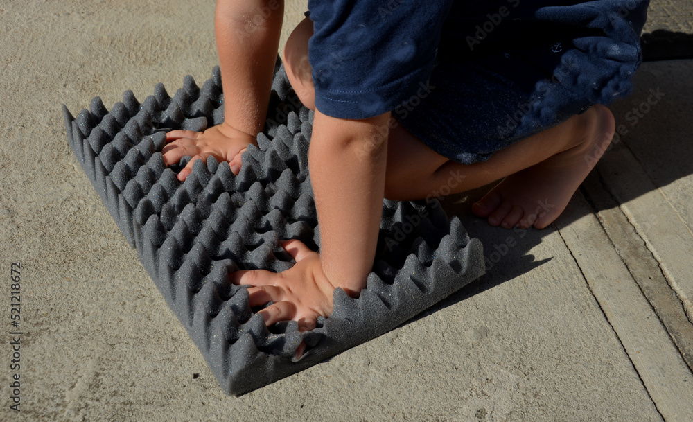 a boy who steps on a foamy dark styrofoam plate. he practices feeling