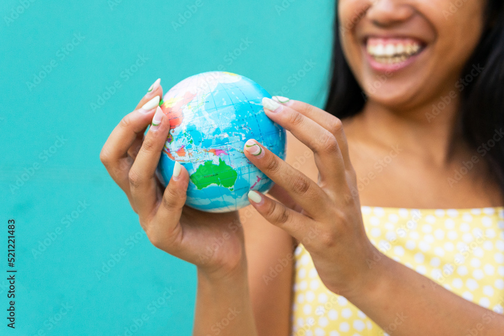 Anonymous happy Asian woman looking at small globe Anonymous happy Asian woman looking at small globe