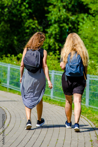 Two girlfriends walk along a path in the Park 