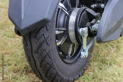 Rubber wheels connected to a brushless motor on an electric vehicle with rear view of vehicle standing on a lawn