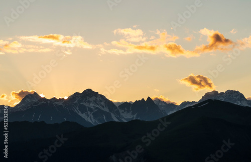 Beautiful mountains landscape on the sunset. High snow covered mountains in the fog and clouds. 