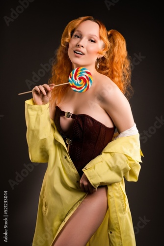 Seductive female model with lollipop in hand smiling at camera