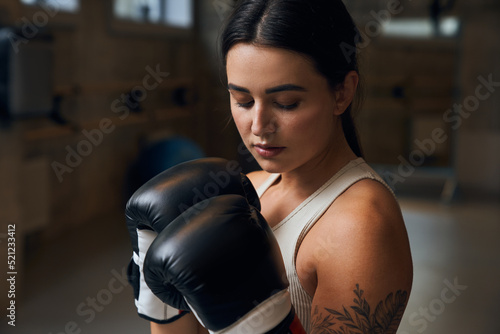 Young tired woman wearing boxing gloves relaxing after doing boxing training at the gym © Yakobchuk Olena
