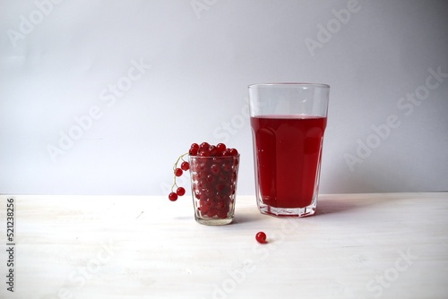 Fresh red currant juice glass and redcurrant berries on white background