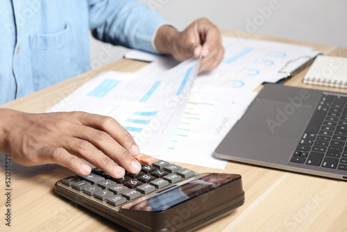 Businessman using calculators and laptops to calculate financial figures working in the office. Financial accounting concept
