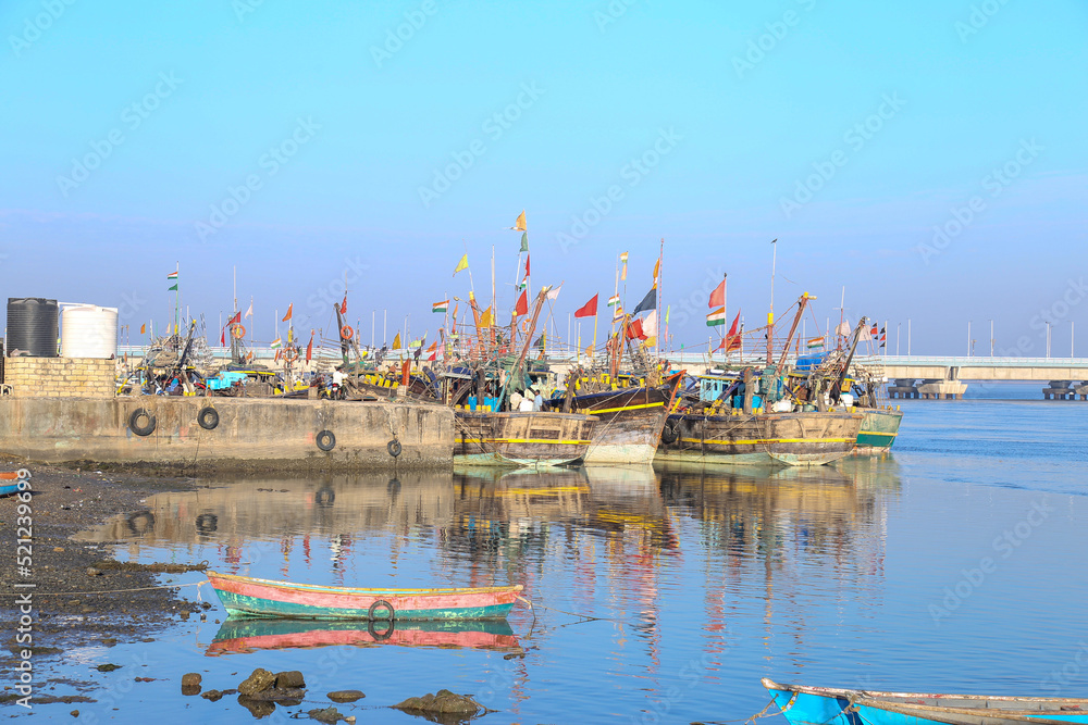 Fototapeta premium boats, empty tables and quaint buildings along the promenade at Fisherman's Village on a sunny day in india