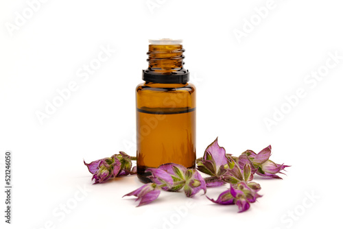 A bottle of essential oil with fresh blooming clary sage twigs on white background.