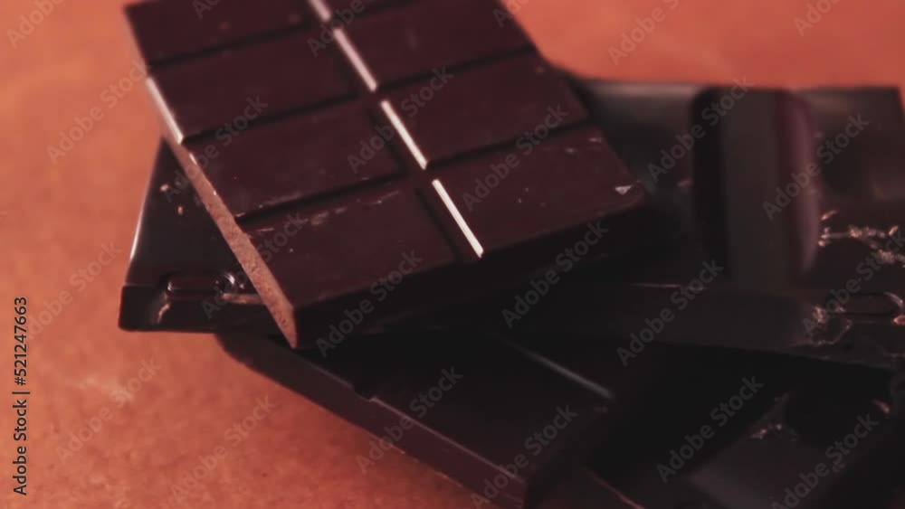 Tiles of bitter dark chocolate rotating, close up to details and texture of the product. Brain food healthy natural cocoa delicacy Tiles of bitter dark chocolate rotating, close up to details and texture of the product. Brain food healthy natural cocoa delicacy