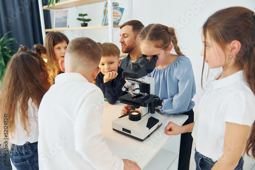 Working with the microscope. Group of children students in class at school with teacher
