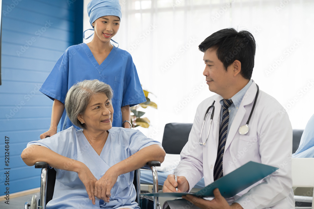 Obraz premium Doctor, nurse and elderly patient woman sit on wheelchair. Male doctor visit and writing note to seek advice with elderly asian woman on wheelchair at the hospital